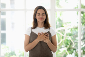 Woman,holds,both,hands,on,heart,symbol,of,gratitude,closed 